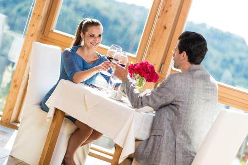 圣马丁安德达斯艾森伯格酒店的坐在桌子上戴酒杯的男人和女人