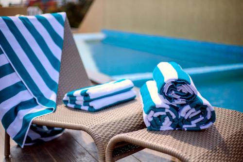 科钦Sidra Pristine Hotel and Portico Halls的游泳池旁的椅子上摆放着两条毛巾