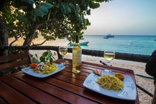 蓬塔露奇亚Paradise Island Beach Resort的海滩上的一张桌子,上面放着两杯葡萄酒和面食