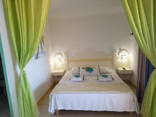 圣安娜les hauts de caritan的一间卧室配有一张带两盏灯和绿窗帘的床。