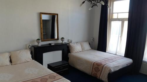 登博斯All-In Hotel的卧室配有两张床、镜子和窗户。