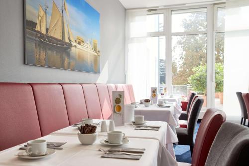 不来梅·弗格萨克弗格萨克阿特兰提卡酒店的餐厅的一排桌子和粉红色的椅子