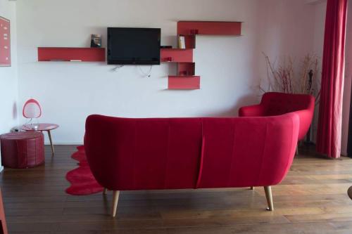 维琪奥港伊莫布海洋公寓的客厅设有一张红色沙发,配有电视