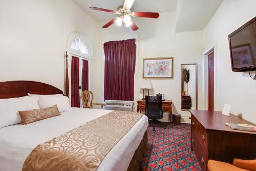 新奥尔良新奥尔良住宿加早餐旅馆的一间卧室配有一张带吊扇的床和一张书桌。