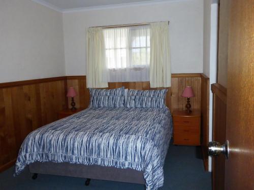 布里德波特鸭嘴兽公园乡村度假酒店的一间卧室配有一张带窗户和两盏灯的床。