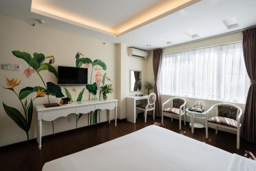 胡志明市Asian Ruby Center Point Hotel & Spa的一间卧室配有一张床,墙上配有电视