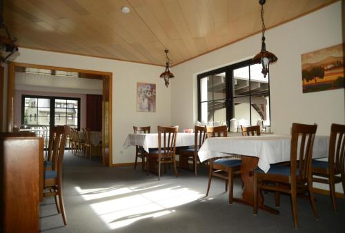 维林根莱瑟歌尼旅馆的一间配备有白色桌椅的用餐室