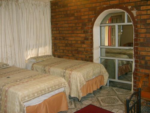 Brakpan迎宾旅馆的一间设有两张床和砖墙的房间