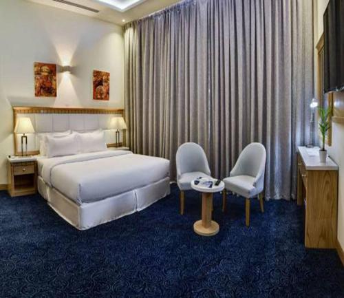 利雅德Golden Dune Hotel AlFayhaa的酒店客房带一张床、一张桌子和椅子