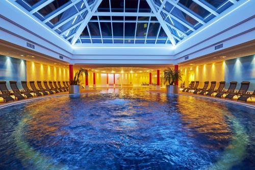 腓特烈罗达腓特烈罗达H+水疗酒店的一个带椅子的房间中间的一个大型游泳池