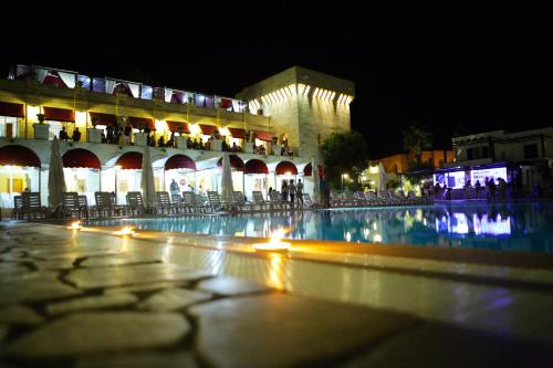 莱乌卡Messapia Hotel & Resort的一座晚上有水池的建筑