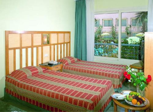 赫尔格达海之园酒店的一间卧室设有两张床和一张带一碗水果的桌子。