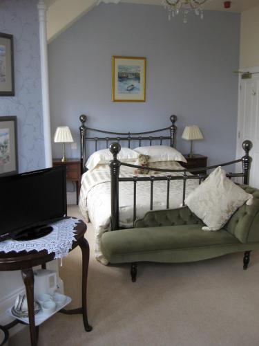 巴基Struan House的一间卧室配有一张带绿色沙发的床和一台电视。