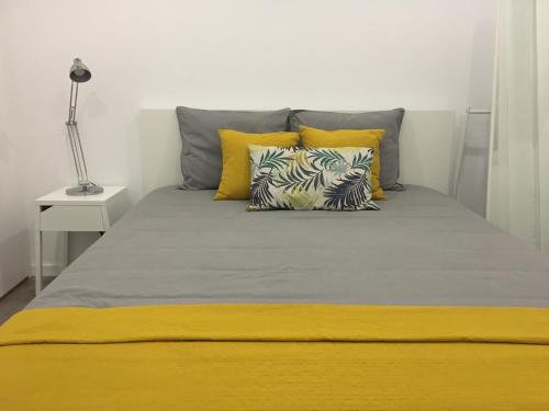 里斯本Lisboa Comfort Apartment的卧室里一张带黄色和灰色枕头的床