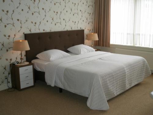 海牙怡东酒店的卧室配有一张带白色棉被的大床