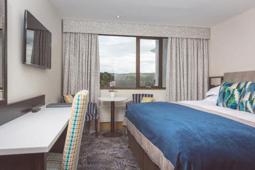 贝尔法斯特黑斯廷斯斯图尔芒特酒店的配有一张床、一张书桌和一扇窗户的酒店客房