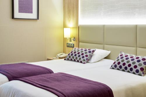 博讷博纳基里亚德酒店的两张位于酒店客房的床铺,配有紫色枕头