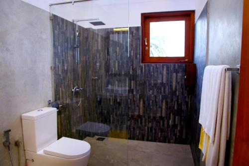 阿鲁特伽马Malu Banna的一间带卫生间和玻璃淋浴间的浴室