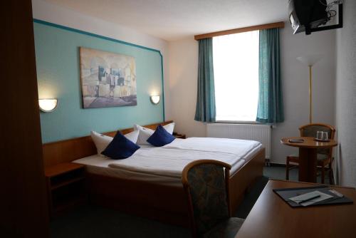 NiederwiesaHotel Garni Brauhof Niederwiesa的酒店客房设有一张蓝色墙壁的床和窗户。