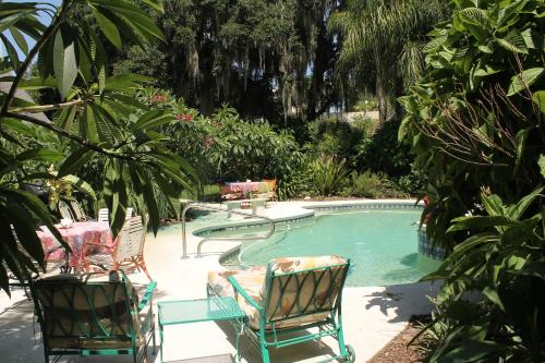 芒特多拉Heron Cay Lakeview Bed & Breakfast的游泳池配有2把椅子、1张桌子和1张桌子及椅子