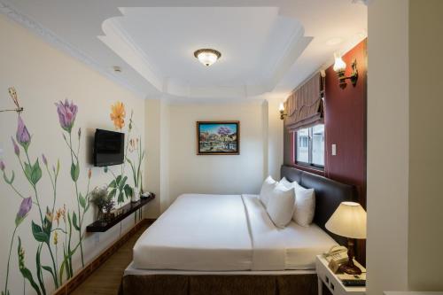 胡志明市Asian Ruby Center Point Hotel & Spa的一间酒店客房,配有一张床和一台电视