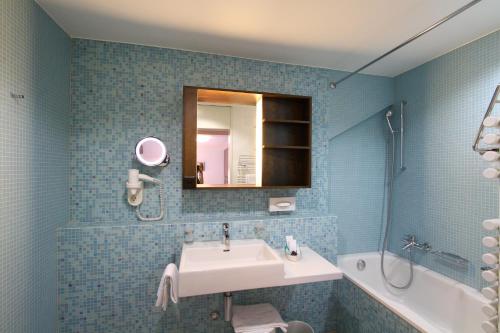 布鲁格布鲁格特米纳斯酒店的浴室配有盥洗盆、镜子和浴缸