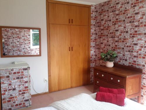 奥阿库尼Riversong的一间卧室设有砖墙、一张床和一个梳妆台
