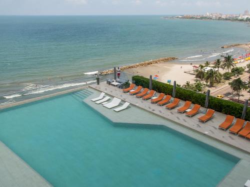 卡塔赫纳Luxury Alojamientos Namaste-Morros City的享有带椅子的游泳池和海滩的上方景色