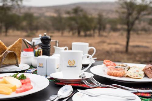 塞伦盖蒂国家公园Ole Serai Luxury Camp的餐桌,盘子,咖啡
