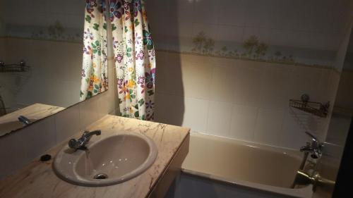 维拉福林Apartamentos Versailles的浴室配有盥洗盆和浴缸。