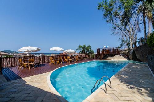 乌巴图巴科基耶酒店的一个带桌子和遮阳伞的游泳池以及大海