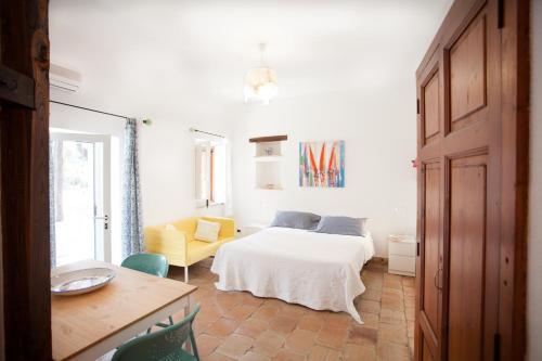 陶尔米纳Villaggio Placido的卧室配有白色的床和黄色椅子