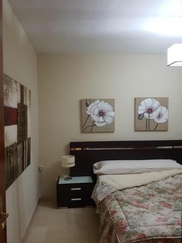 塞维利亚爱德华多拿督公寓的卧室配有一张床,墙上挂着两朵鲜花
