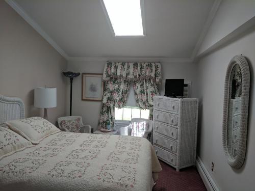 五月岬郡Inn At The Park - The Cottage的一间卧室配有一张床、一个梳妆台和一扇窗户。