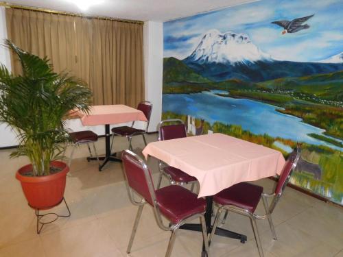 里奥班巴Hostal Alborada Riobamba的配有桌椅的房间和一幅山画