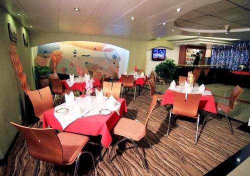 达卡La Vinci Hotel的一间设有红色桌椅和牛壁画的餐厅