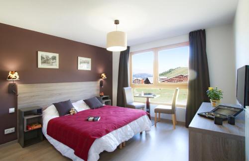 普拉涅村Résidence Prestige Odalys Front de Neige的一间卧室配有红色的床、一张书桌和一个窗户。