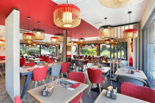勒芒宜必思乐梦呓彭琉的餐厅设有红色的桌椅和吊灯