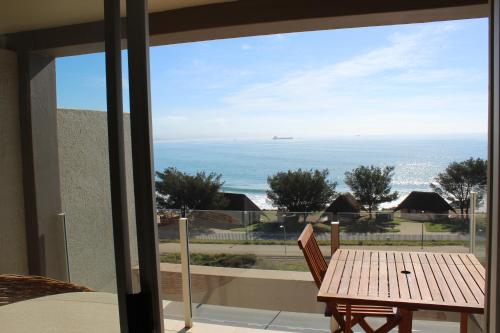 莫塞尔湾Seafront Apartment in Mossel Bay的阳台配有桌子,享有海景。