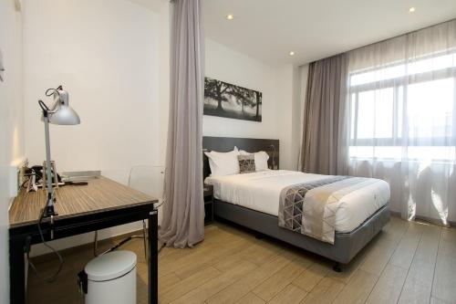 基苏木Imperial Hotel Express的一间卧室配有一张床、一张书桌和一个窗户。