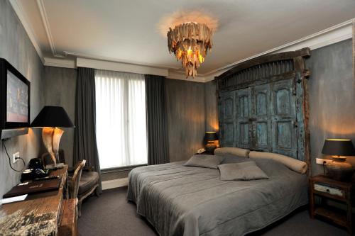 赫尔蒙德Golden Tulip West Ende的一间卧室配有一张大床和一个吊灯。