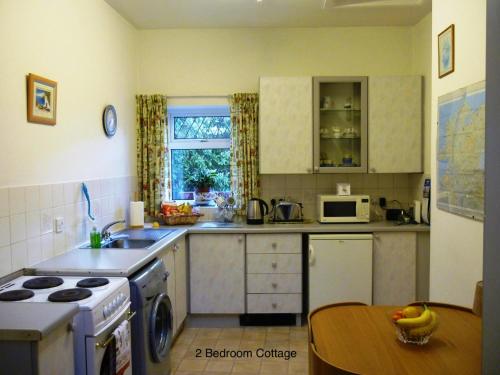 贝尔法斯特Hallmount Cottage - Belfast的厨房配有水槽、炉灶和桌子