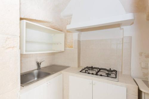 奥斯图尼Dimora Alfonso Pomes的白色的厨房设有水槽和炉灶。