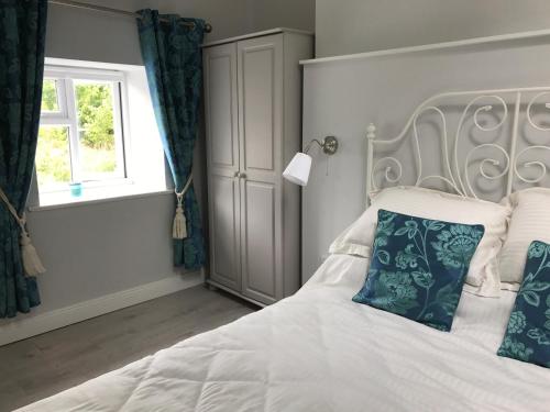 Ballymore EustaceHobbit Hollow的卧室配有白色床、蓝色枕头和窗户
