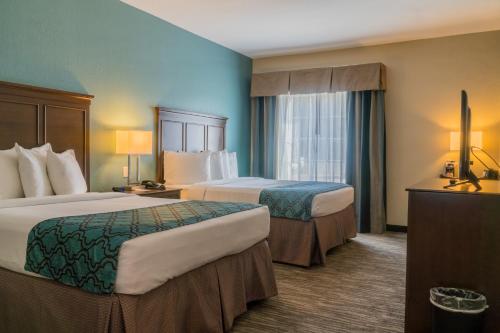 DeQuincyHeritage Place Hotel and Suites的酒店客房设有两张床和窗户。