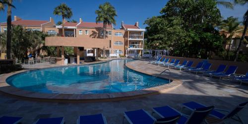 棕榈滩迪维荷兰​​村海滩度假酒店的一座带蓝色椅子的游泳池和一座建筑