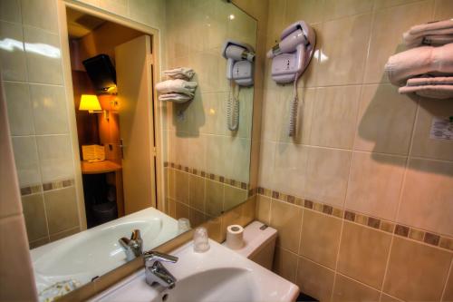 巴黎三车站酒店的一间带水槽、浴缸和镜子的浴室