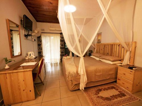 卢萨卡棕榈木山林小屋的一间卧室配有一张天蓬床、一张桌子和一个水槽