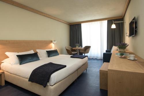 博尔米奥穆布雷赛托雷丽里特酒店的酒店客房设有一张大床和一张桌子。