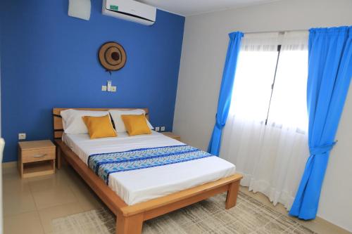 阿比让Residence Alizee的一间卧室配有一张蓝色墙壁的床和一扇窗户